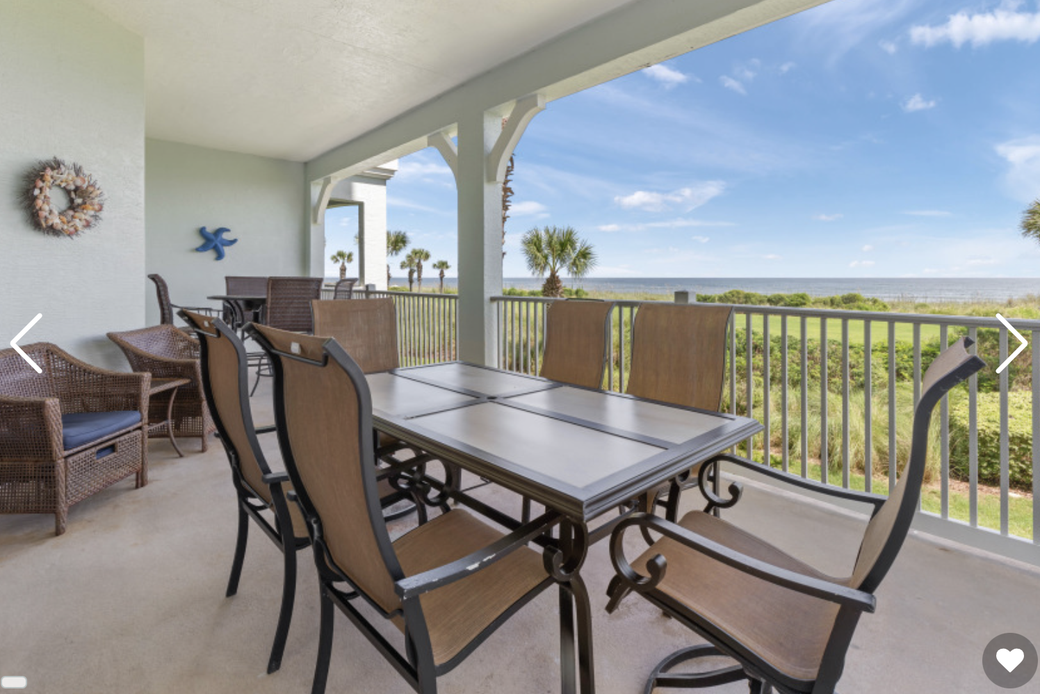The condo's covered oceanfront balcony with dining set and ocean beyond